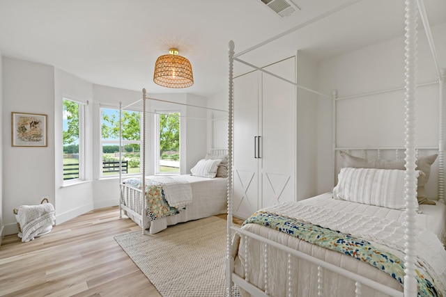 bedroom featuring baseboards, visible vents, and light wood finished floors