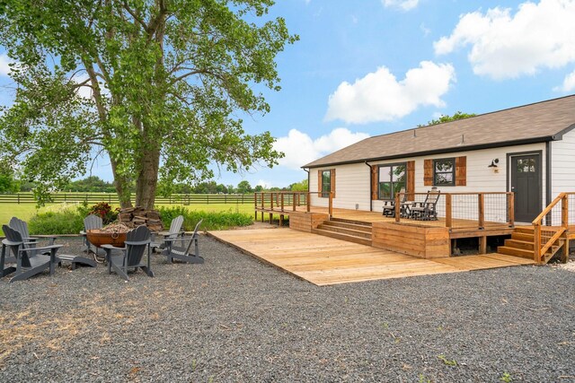 exterior space with a shingled roof, a fire pit, fence, and a deck