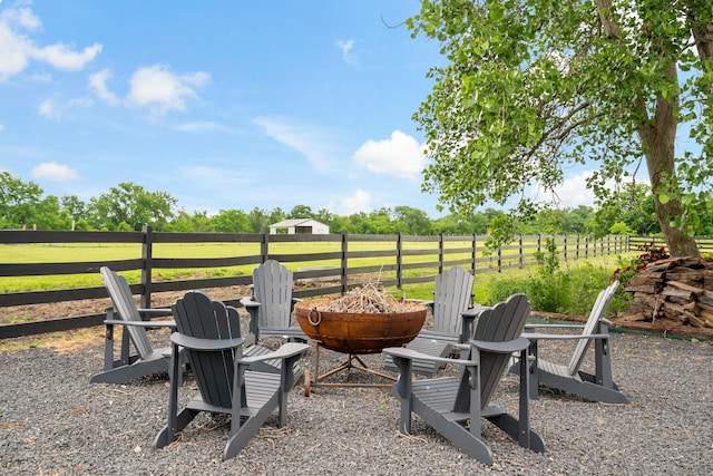 view of yard with an outdoor fire pit, fence, and a rural view