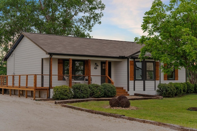 ranch-style home featuring a porch, roof with shingles, and a front yard