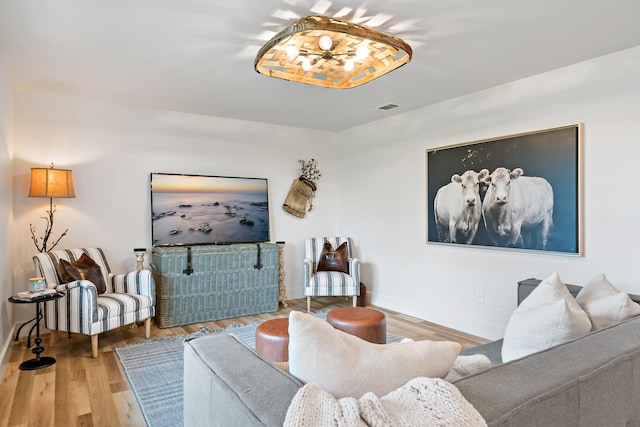 living area featuring baseboards, wood finished floors, and visible vents