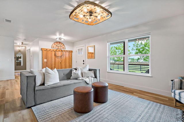 living room with baseboards, visible vents, and light wood finished floors
