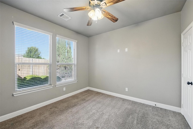 carpeted empty room with baseboards, a ceiling fan, and visible vents