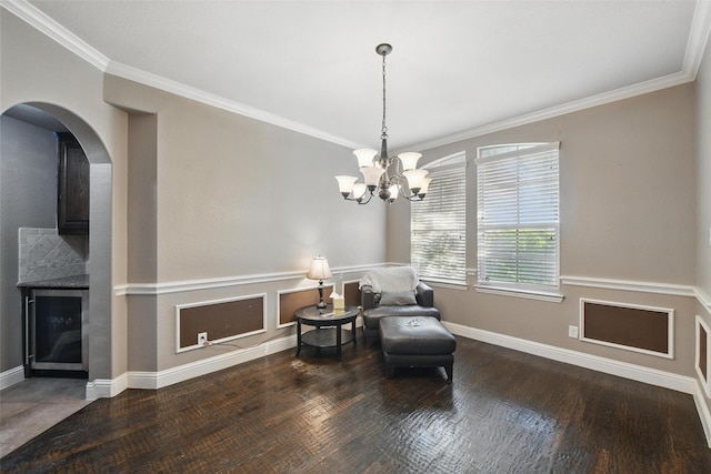 sitting room featuring a chandelier, wood finished floors, baseboards, and ornamental molding