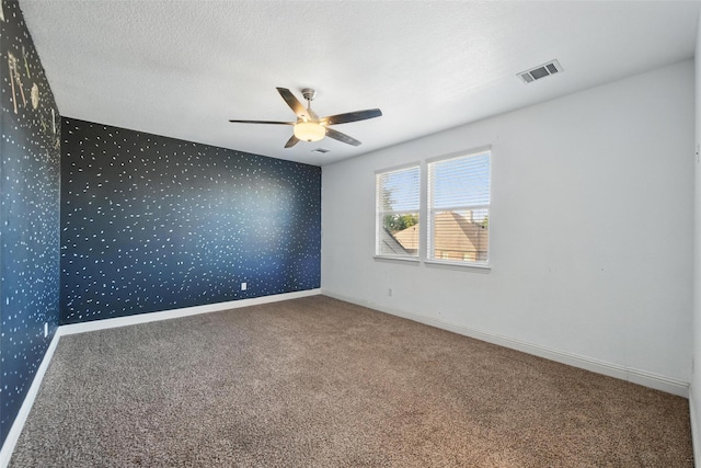 carpeted spare room with ceiling fan, baseboards, wallpapered walls, and visible vents