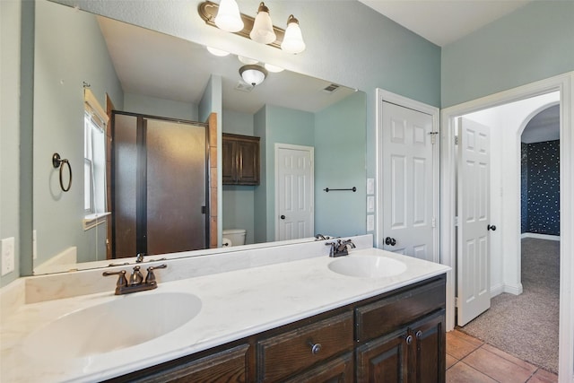 full bathroom featuring a sink, a shower stall, double vanity, and toilet