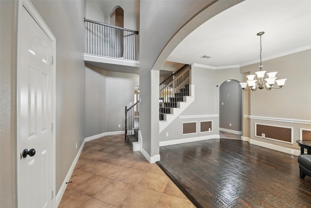 entrance foyer featuring stairway, visible vents, arched walkways, baseboards, and a chandelier