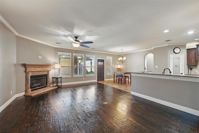 unfurnished living room featuring arched walkways, baseboards, a fireplace with raised hearth, ceiling fan with notable chandelier, and wood finished floors