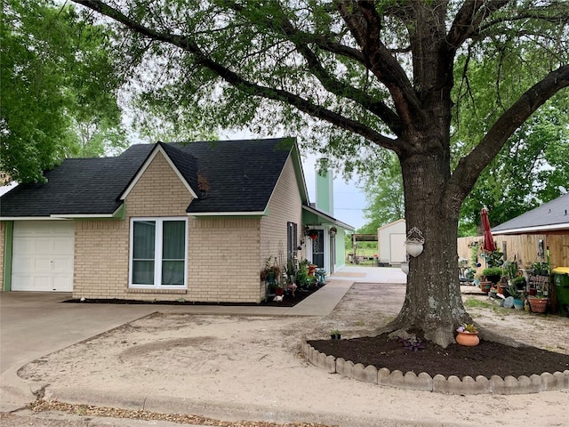 view of home's exterior featuring an outbuilding, driveway, brick siding, a shingled roof, and a shed