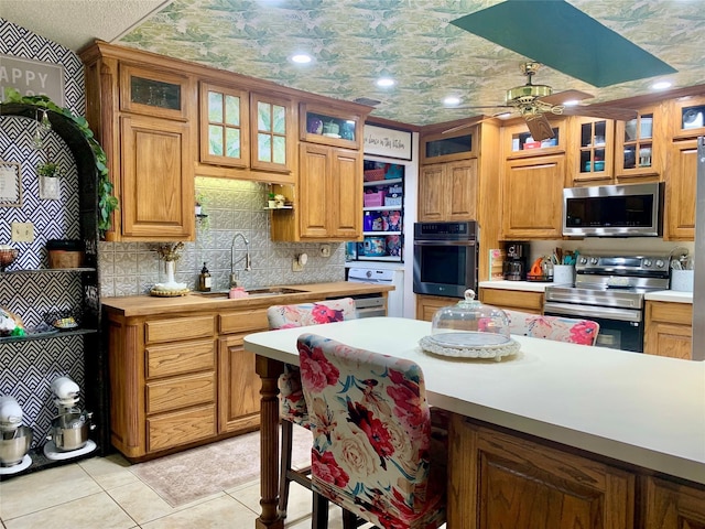 kitchen featuring light countertops, appliances with stainless steel finishes, a ceiling fan, and a sink