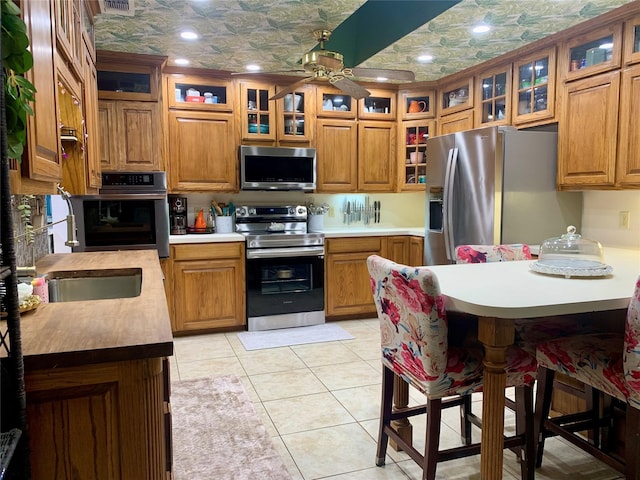 kitchen with an ornate ceiling, brown cabinets, appliances with stainless steel finishes, and a ceiling fan
