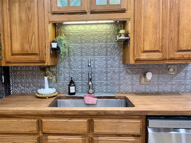 kitchen with tasteful backsplash, a sink, wooden counters, brown cabinetry, and dishwasher