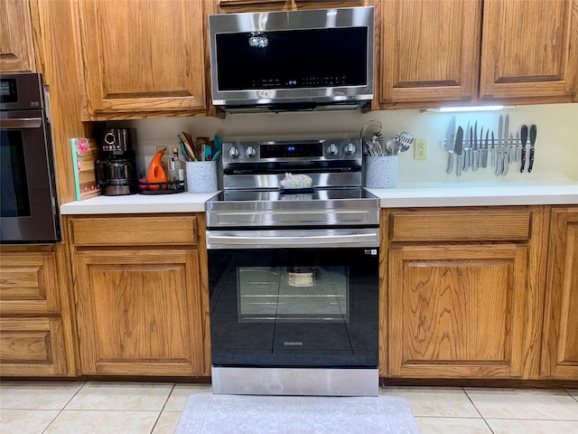 kitchen featuring brown cabinets, appliances with stainless steel finishes, and light tile patterned flooring