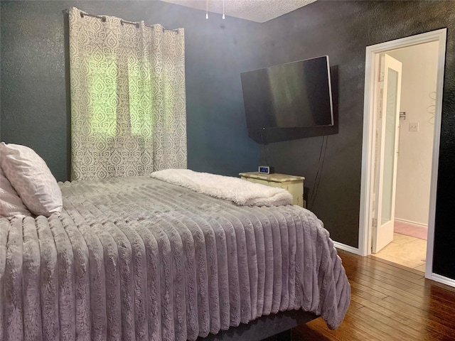 bedroom with baseboards and wood finished floors