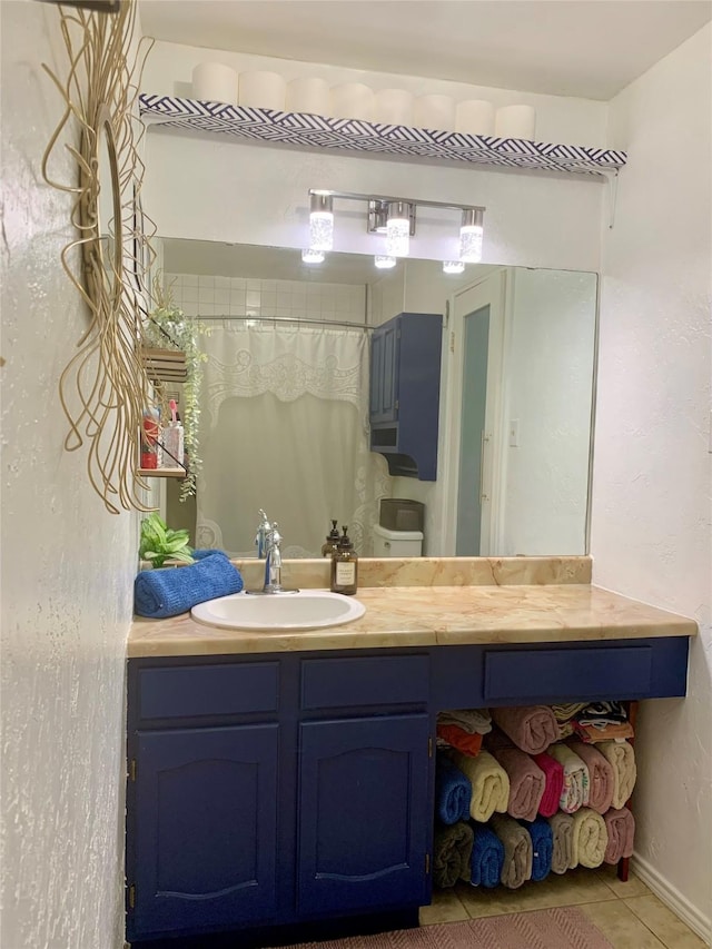 full bath featuring baseboards, vanity, and tile patterned flooring
