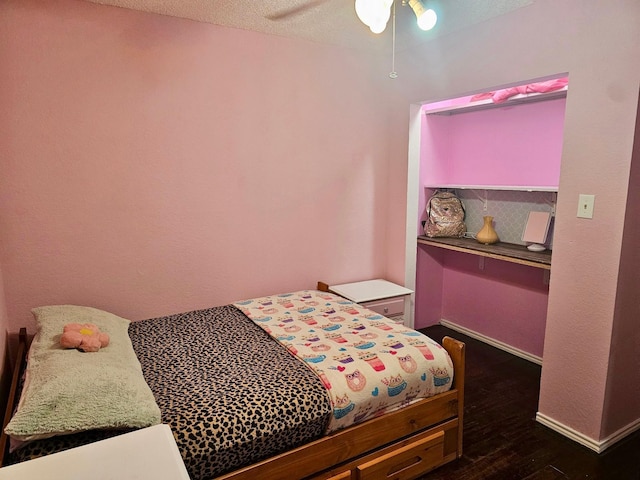 bedroom with dark wood-type flooring, a ceiling fan, and baseboards