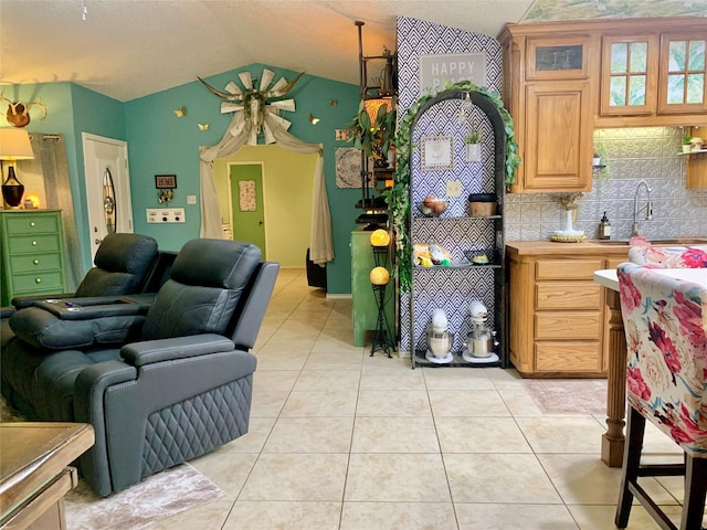 kitchen with a sink, open floor plan, lofted ceiling, light countertops, and light tile patterned floors