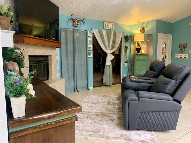 living area with a glass covered fireplace, tile patterned flooring, and a textured ceiling