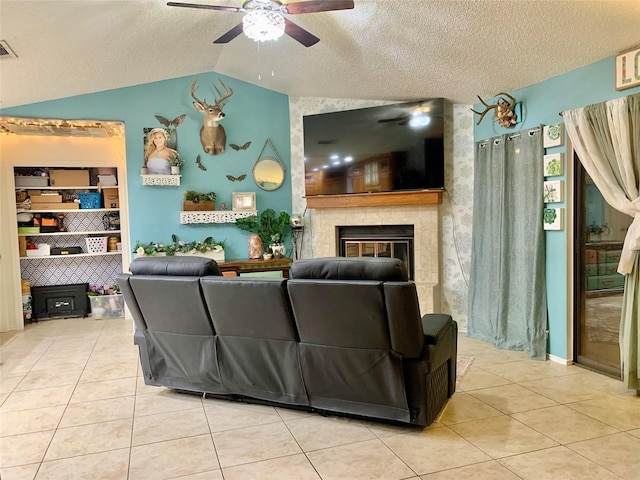 living area featuring vaulted ceiling, a textured ceiling, tile patterned floors, and a ceiling fan