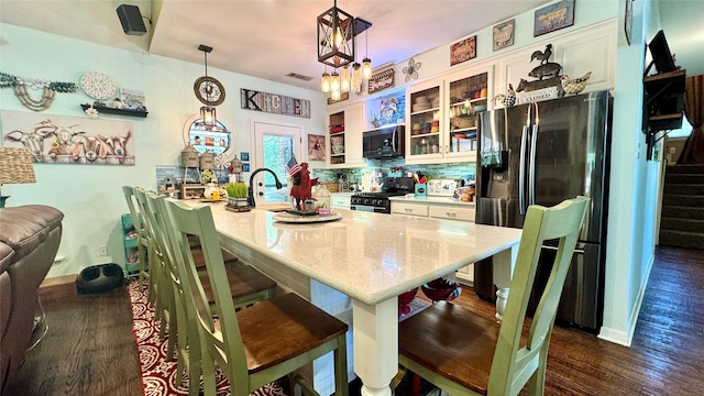 kitchen featuring range with gas cooktop, a kitchen breakfast bar, glass insert cabinets, white cabinets, and stainless steel refrigerator with ice dispenser