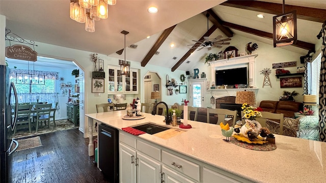 kitchen featuring a sink, black appliances, open floor plan, vaulted ceiling with beams, and white cabinetry