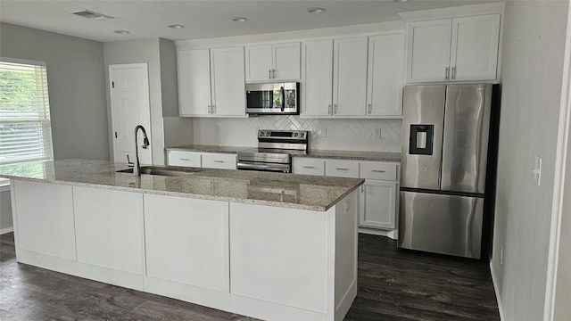 805 S 4th St, Bonham, TX 75418 - kitchen with stainless steel appliances, a sink, dark wood finished floors, a kitchen island with sink, and white cabinets