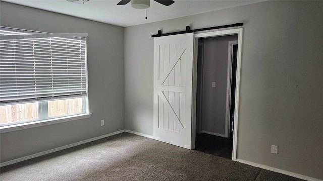 805 S 4th St, Bonham, TX 75418 - unfurnished bedroom featuring carpet floors, a barn door, baseboards, and a ceiling fan