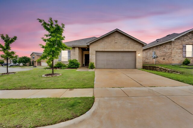 ranch-style home featuring an attached garage, concrete driveway, a front yard, and brick siding