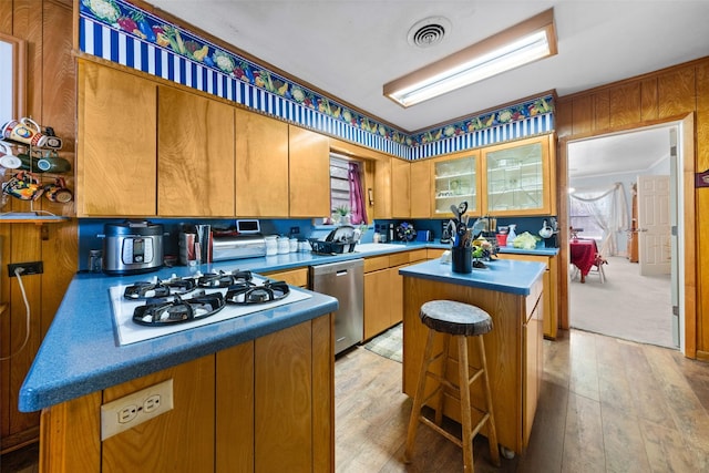1302 E Mclennan Ave, Mart, TX 76664 - kitchen with stainless steel dishwasher, white gas stovetop, a kitchen island, light wood-style floors, and glass insert cabinets