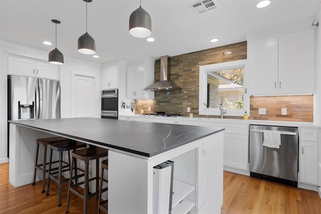 kitchen featuring wall chimney range hood, appliances with stainless steel finishes, backsplash, and visible vents