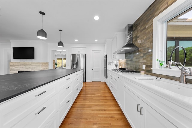 kitchen featuring a sink, appliances with stainless steel finishes, wall chimney exhaust hood, and a healthy amount of sunlight