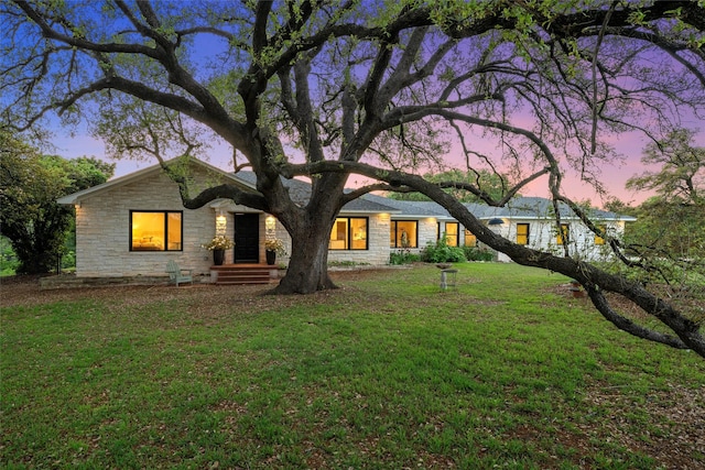 rear view of property featuring a yard and stone siding