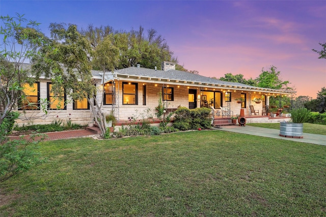 back of house featuring a yard, a porch, and stone siding