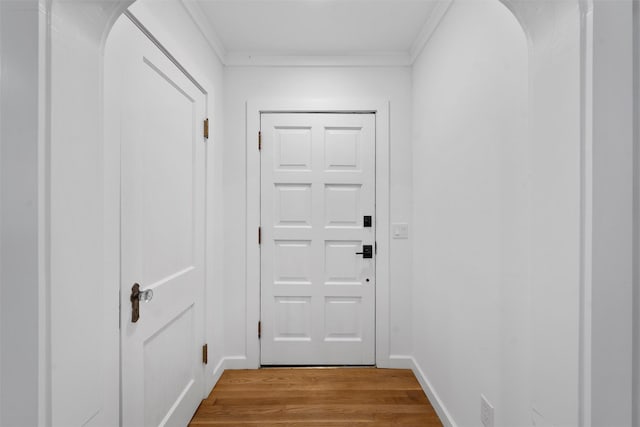 entryway with crown molding, baseboards, and light wood-style flooring