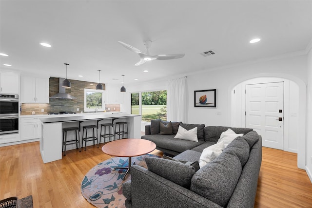 living room with arched walkways, visible vents, ornamental molding, and recessed lighting