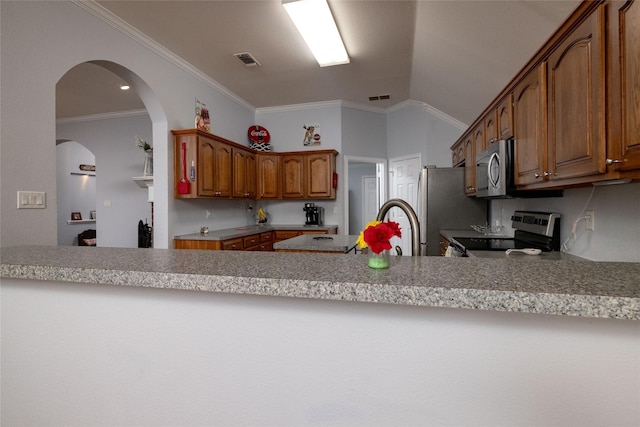 516 Hazelnut Ct, Saginaw, TX 76179 - kitchen featuring appliances with stainless steel finishes, a peninsula, brown cabinetry, crown molding, and vaulted ceiling