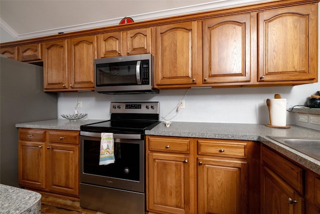 516 Hazelnut Ct, Saginaw, TX 76179 - kitchen with stainless steel appliances, brown cabinetry, and dark wood-style flooring