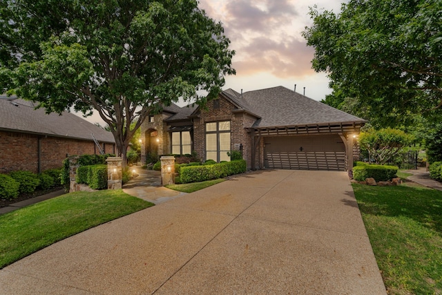 view of front facade featuring brick siding, a front lawn, concrete driveway, an attached garage, and a shingled roof