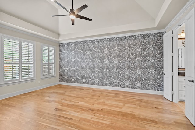 spare room featuring light wood-style floors, a raised ceiling, a ceiling fan, and wallpapered walls