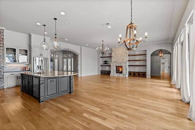kitchen featuring crown molding, arched walkways, a sink, and a notable chandelier