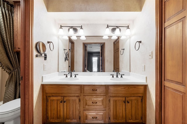 full bathroom featuring a sink, double vanity, and toilet