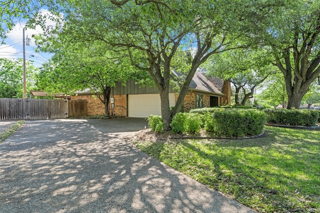 view of side of home featuring brick siding, fence, and aphalt driveway