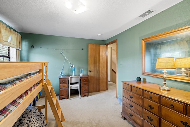 bedroom featuring a textured ceiling, visible vents, and light carpet