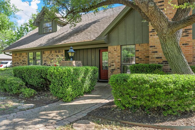 view of front of home with board and batten siding, brick siding, and a shingled roof