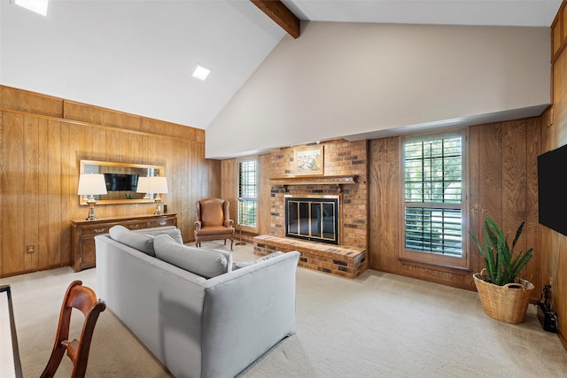 living area featuring a healthy amount of sunlight, beamed ceiling, a brick fireplace, wood walls, and high vaulted ceiling