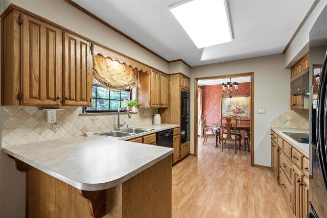 kitchen featuring a peninsula, a sink, a chandelier, brown cabinets, and light countertops