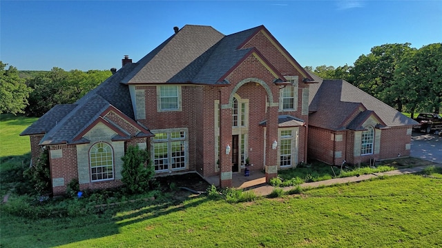 traditional-style house featuring brick siding, roof with shingles, and a front lawn