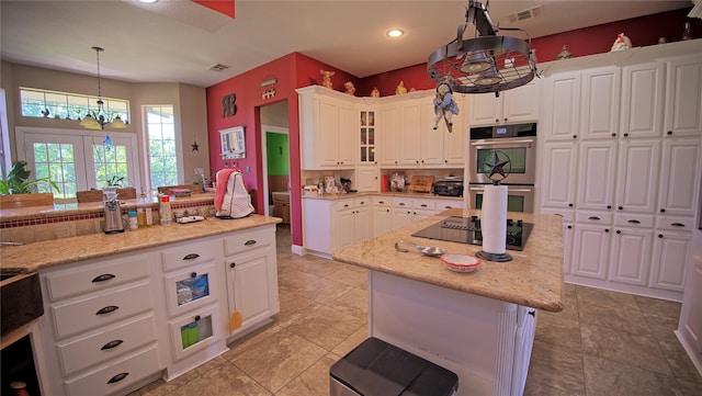 kitchen featuring a center island, double oven, an inviting chandelier, black electric cooktop, and visible vents