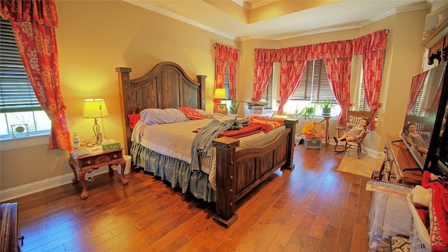 bedroom featuring baseboards, ornamental molding, hardwood / wood-style floors, and a raised ceiling
