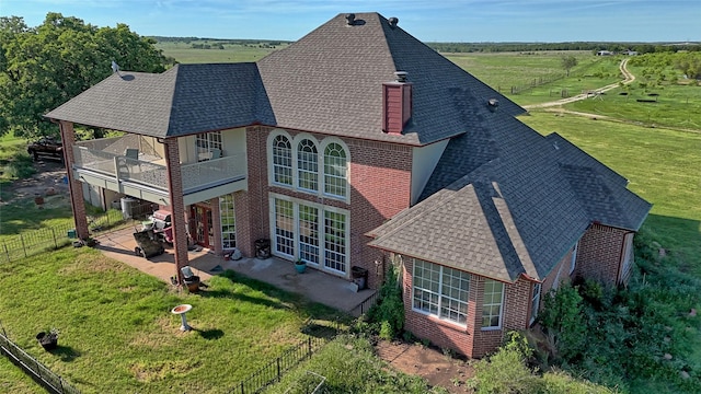 rear view of property featuring a lawn, brick siding, a patio area, and a shingled roof